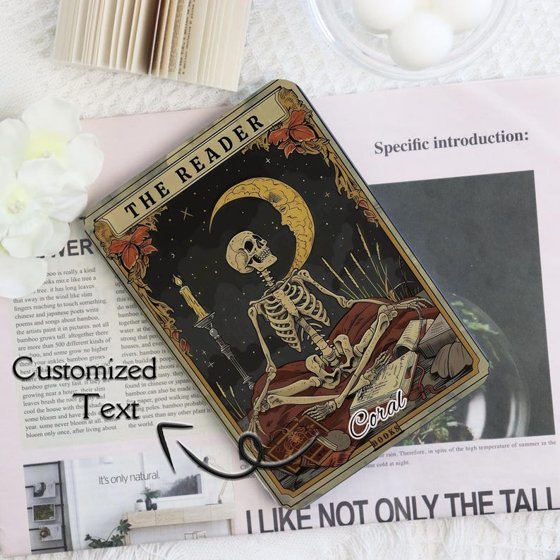 K&ouml;nnte beinhalten: Rechteckige Tarotkarte mit einem Skelett unter einem Mond und Sternen. Die Karte tr&auml;gt oben die Aufschrift "THE READER" und unten "Coral BOOKS". Das Design hat einen Vintage- und Gothic-Stil.
