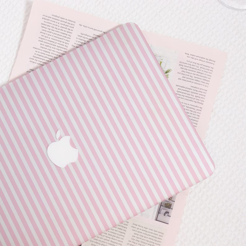 May include: A pink and white striped laptop cover with the Apple logo. The cover is on top of a pink paper with text. The background is a white surface.