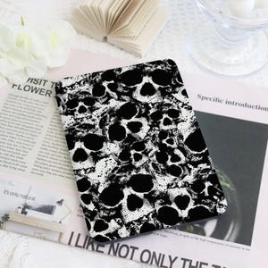 Op de afbeelding: Een rechthoekig object toont een zwart-wit schedelpatroon. Het ontwerp bevat talrijke schedels met een gestippelde textuur. De tekst "I LIKE NOT ONLY THE" is zichtbaar aan de onderkant van het object.