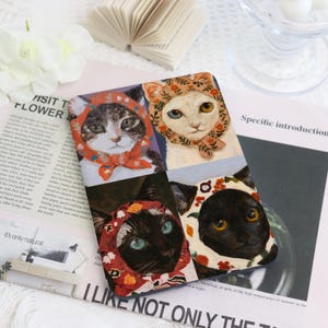 May include: A collage of four illustrations of cats wearing colorful head coverings. Each cat has a different colored head covering with a floral pattern. The cats are all looking at the viewer. The background is a light blue color.