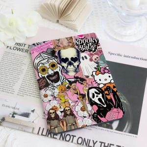 May include: Pink Halloween-themed phone case featuring a collage of spooky characters, including a skull with heart-shaped eyes, a clown, a ghost, and Hello Kitty. The case is decorated with flowers and the text "Spooky Babe."