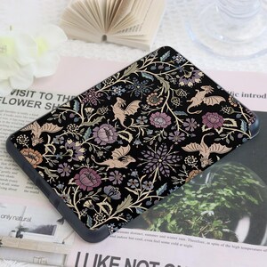 May include: Black phone case with a floral and dragon pattern. The design features stylized flowers in shades of purple, peach, and blue, with beige dragons on a black background. The case has a rounded edge.