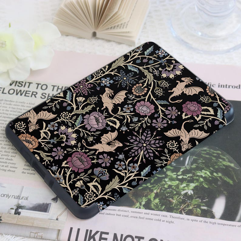 May include: Black phone case with a floral and dragon pattern. The design features stylized flowers in shades of purple, peach, and blue, with beige dragons on a black background. The case has a rounded edge.