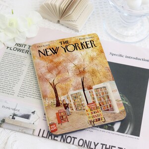 May include: A rectangular coaster featuring a vintage "The New Yorker" magazine cover illustration. The cover art depicts a fall scene with trees, bookshelves, and figures. The text "Oct. 18, 1976" and "Price 75 cents" are visible.