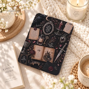 May include: A black e-reader cover featuring a dark, gothic-inspired collage of a raven, a crescent moon, a mirror with the text I WOULD BURN THE WORLD FOR YOU, a candle, a dagger, a potion bottle, a key, and an open book with a castle.