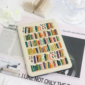 Peut inclure: Une housse de liseuse rectangulaire au fond crème ornée d'un motif répétitif d'étagères horizontales remplies de livres colorés et de petites illustrations botaniques vertes, incluant des feuilles et des fleurs dans des tons de vert, orange et bleu.