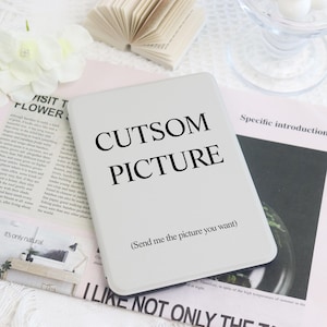 Op de afbeelding: Een wit rechthoekig product met de tekst "CUTSOM PICTURE" in het zwart. Daaronder staat de zin "(Send me the picture you want)". Het product ligt op een tijdschrift met tekst en een bloem.