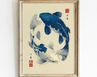 以下が含まれることがあります： クリーム色の背景に2匹の鯉が円を描くように配置された額装アートプリント。1匹は濃い青色、もう1匹は白地に青い斑点模様。プリントには黒い日本語の書道と赤い四角い印章が含まれています。