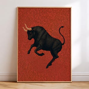 May include: A rectangular framed wall art print featuring a black bull with golden horns in a dynamic leaping pose. The bull is set against a textured, deep red background composed of intricate, swirling lines that create a sense of movement.