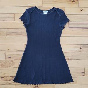 May include: A navy blue ribbed knit dress with short sleeves and a flared skirt. The dress has a scoop neckline and a scalloped hemline. The Esprit brand label is visible at the neckline. The dress is made of a soft, stretchy material.