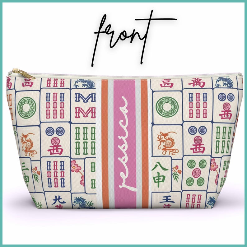 May include: A cream-coloured cosmetic bag with a gold zip, decorated with a pattern of colourful Mahjong tiles. A pink vertical stripe with the name "Jessica" in white script is centred on the bag.