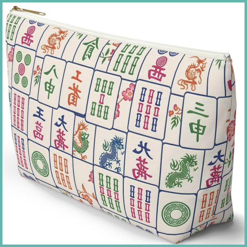 May include: Cream-coloured zippered pouch with a repeating pattern of colourful Mahjong tiles. The tiles display various symbols, dragons, and Chinese characters in shades of red, green, blue, and orange. A gold-coloured zip secures the top.