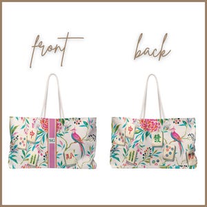 May include: A tote bag shown from the front and back, featuring a white background with a colorful pattern of mahjong tiles, pink birds, and green foliage. The front view includes a vertical pink stripe with the letters SG in the center.
