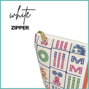 May include: A white zippered pouch with a gold zip pull. The pouch features colourful Mahjong tile designs. The word "white" is written in cursive above the word "ZIPPER".