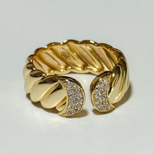 May include: A gold ring with a twisted band and clear stones set in the sides. The ring is open on one side.