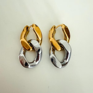 May include: A pair of gold and silver hoop earrings with a chain link design.
