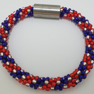 May include: A red, white, and blue beaded bracelet with a silver magnetic clasp.