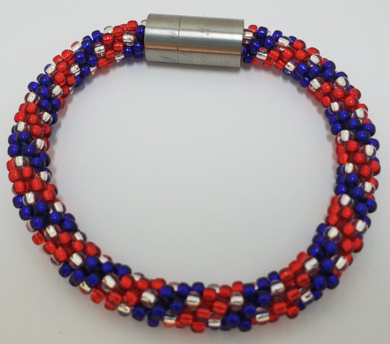 May include: A red, white, and blue beaded bracelet with a silver magnetic clasp.