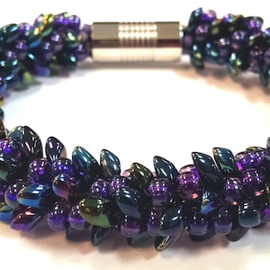 Könnte beinhalten: Ein Armband aus Perlen mit einem Magnetverschluss. Die Perlen sind irisierend und haben eine Farbgebung in Lila, Blau und Grün.