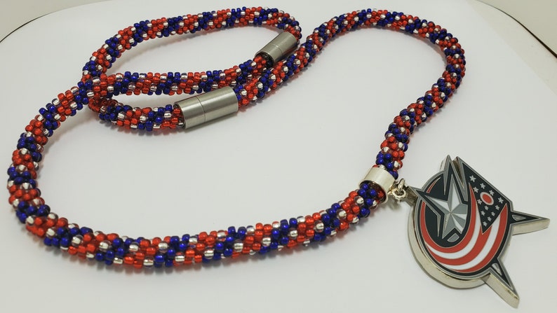 May include: A red, white, and blue beaded necklace with a silver magnetic clasp. The necklace has a silver charm with a red, white, and blue star design.
