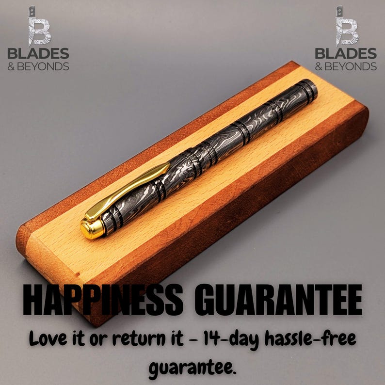Puede incluir: Un bol&iacute;grafo estampado con detalles dorados descansa sobre un portal&aacute;pices de madera. El bol&iacute;grafo presenta un dise&ntilde;o detallado en tonos grises y negros. El portal&aacute;pices est&aacute; hecho de madera clara y oscura. El texto "HAPPINESS GUARANTEE" es visible.