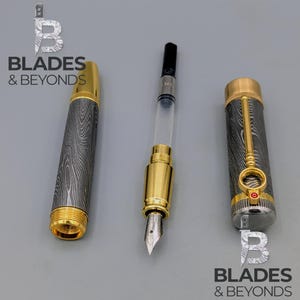 May include: A disassembled fountain pen with a gold-colored nib and accents. The pen's barrel and cap feature a patterned design. The image includes the text "BLADES & BEYONDS".