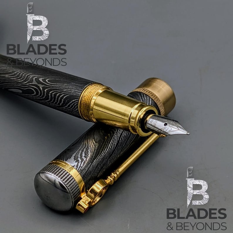 May include: A luxury fountain pen with a patterned black and silver barrel, gold accents, and a silver nib. The pen is partially disassembled, with the cap and body separated. The logo "Blades & Beyonds" is visible.