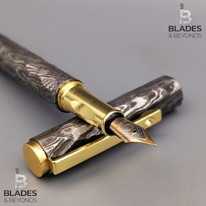 以下が含まれることがあります： 模様入りの濃いグレーとシルバーのボディとゴールドのアクセントが特徴の高級万年筆。 ペンのペン先はブロンズ色です。 ペンのキャップは開いており、ペン先が見えます。 これは筆記具です。