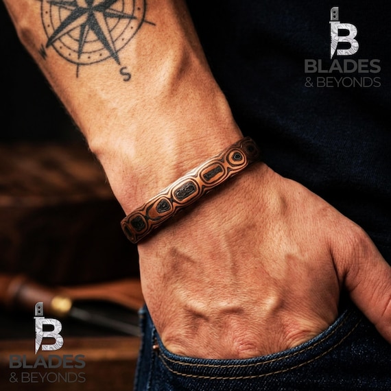 Hand-forged Damascus carbon-copper cuff with a swirling 'Ember Core' pattern — this is actual blacksmithing craft, not a laser-engraved blank.