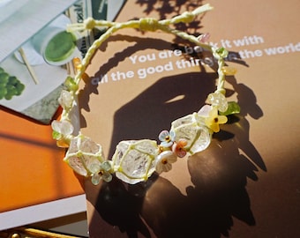 May include: A delicate bracelet made with clear quartz crystals, colorful beads, and a light yellow string. The bracelet features a floral design with small, colorful flowers.
