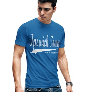 May include: A royal blue t-shirt with a white vintage-style graphic that says "Ipswich Town" with the tagline "It's in the blood".