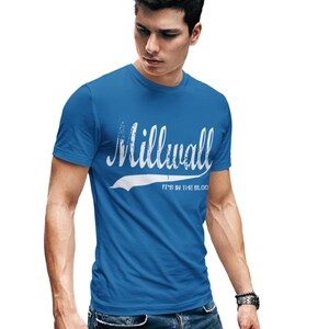 Peut inclure: Un t-shirt bleu royal avec un graphisme blanc de style vintage qui dit "Millwall" avec le slogan "It's in the blood".
