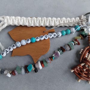 May include: A selection of handmade keychains and accessories. Features a macrame keychain, a beaded keychain with the text "PAPA AMOUR", a gemstone beaded keychain, and a woven figure keychain. The items are in various colours.