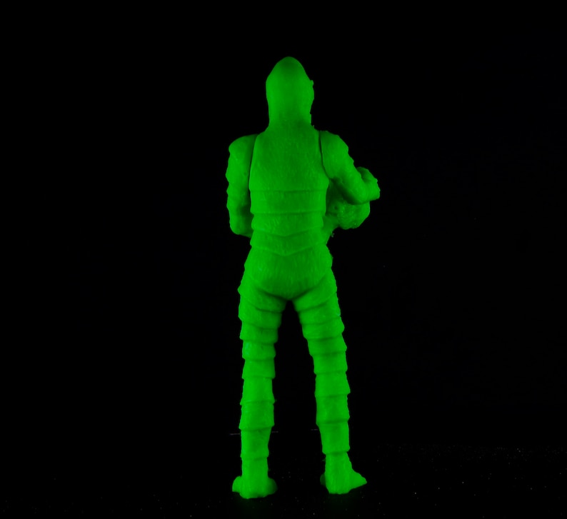 Pu&ograve; includere: Figurina di azione in plastica verde di un mostro con una texture squamosa. La figura &egrave; in piedi con le braccia lungo i fianchi e le gambe leggermente divaricate.