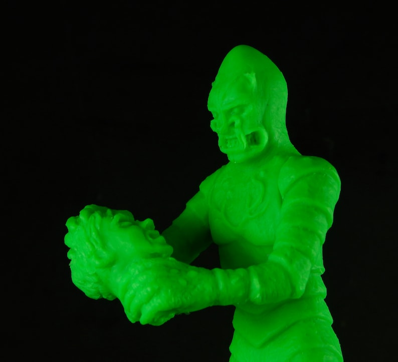 Pu&ograve; includere: Una figura di plastica verde che brilla al buio di un mostro che tiene una figura pi&ugrave; piccola nelle sue mani.