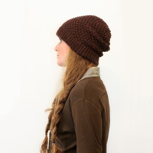 May include: A brown knitted beanie with a textured pattern. The beanie is slouchy and has a fold-over brim.