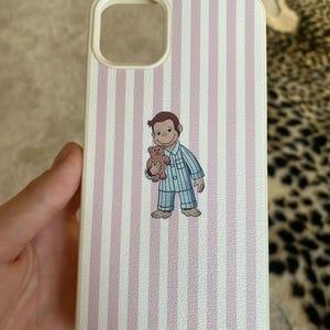 May include: White phone case with vertical pink stripes. The case features a cartoon illustration of a monkey in blue pajamas holding a teddy bear. The case has a camera cutout and a white border.