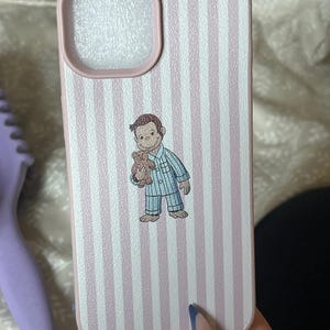 May include: Pink and white striped phone case featuring a cartoon illustration of a monkey in pajamas holding a teddy bear. The case has a pink border around the camera cutout and a matching pink border. The case is designed for a smartphone.