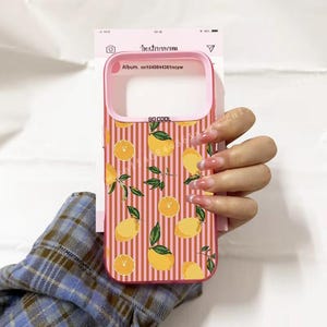 Pode incluir: Capa de telefone rosa com um padrão de listras verticais e ilustrações de limões e folhas. A capa tem uma borda rosa e o texto "SO COOL". A capa do telefone é exibida em um fundo branco com o logotipo do Instagram.