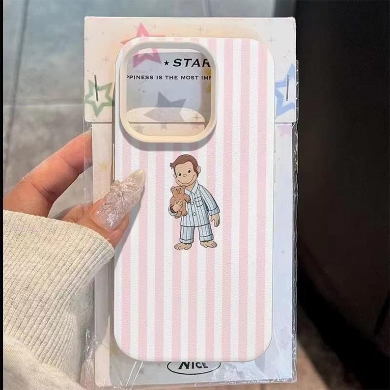 May include: A phone case with a pink and white striped pattern. The case features a cartoon illustration of a boy in pajamas holding a teddy bear. The text "STAR" and "HAPPINESS IS THE MOST IMP" is visible on the case.