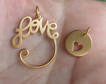 May include: Two gold-tone pendants, one shaped like the word "LOVE" with a swirl at the bottom, and the other a round disc with a cut-out heart shape.