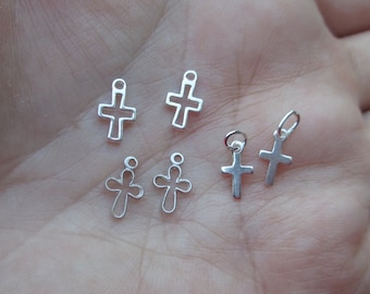 May include: Five silver cross charms of varying sizes. The charms are open and have a smooth, polished finish.