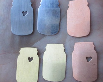 May include: Six metal mason jar charms with a heart cut out. The charms are in different colors, including silver, copper, and gold.
