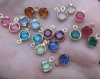 May include: Assortment of colorful glass beads with gold-toned metal loops. The beads are in various colors, including blue, green, red, pink, and purple.