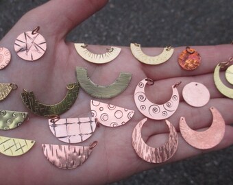 May include: A collection of 16 metal charms in various shapes and sizes, including circles, half-circles, and crescents. The charms are made of copper and brass and feature different textures and patterns, such as swirls, dots, and lines.