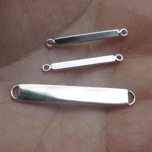 May include: Three silver bar connectors with two loops on each end. The bars are different lengths.