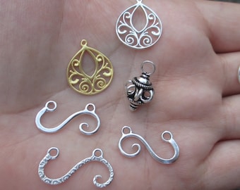 May include: Assortment of silver and gold filigree jewelry findings, including two ornate pendant charms, a small ball charm, and three silver S-shaped connectors.