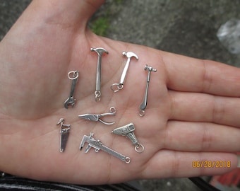 Dije de plata esterlina con forma de martillo, llave inglesa o sierra (un dije). Tú eliges cuál.