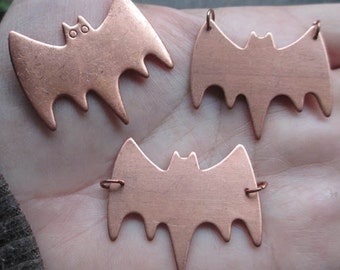 May include: Three copper bat charms with a simple design. Each charm has a hole at the top for hanging.
