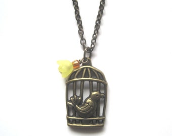 Bird at a cage adorned with Yellow flower. Brass Pendant Necklace. 21 inch brass chain.